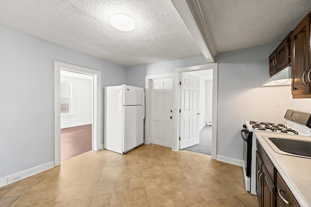 kitchen with freestanding refrigerator, range hood, dark brown cabinetry, a textured ceiling, and gas range