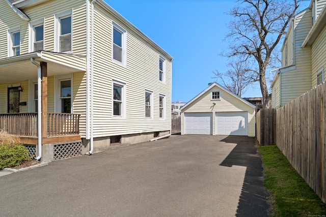 view of side of property featuring a porch, an outdoor structure, fence, and a detached garage