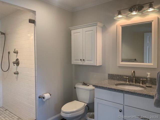 full bath with vanity, toilet, ornamental molding, and tiled shower