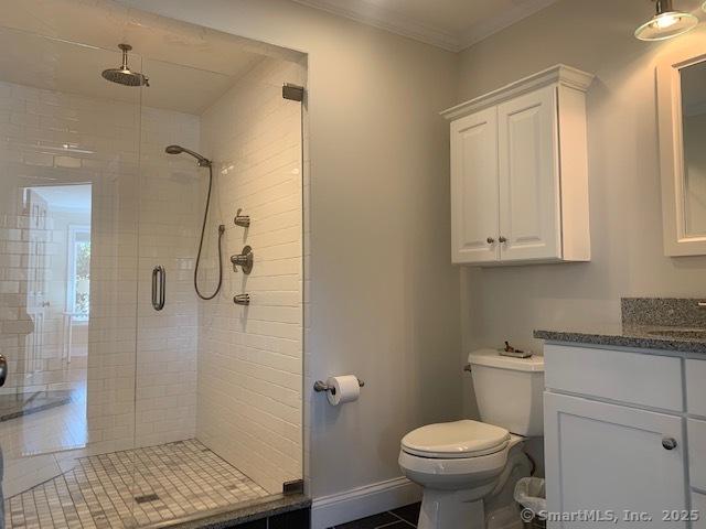 bathroom with vanity, toilet, a stall shower, ornamental molding, and tile patterned flooring