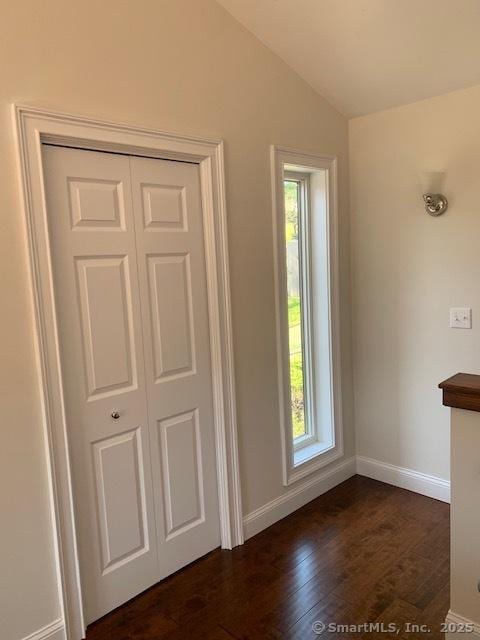 interior space featuring dark wood-style floors, vaulted ceiling, and baseboards