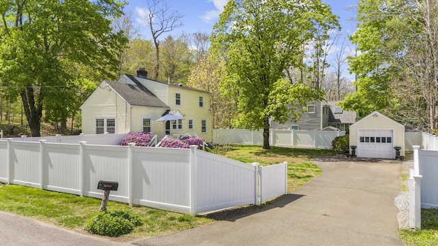 exterior space featuring fence private yard, a garage, an outbuilding, and driveway