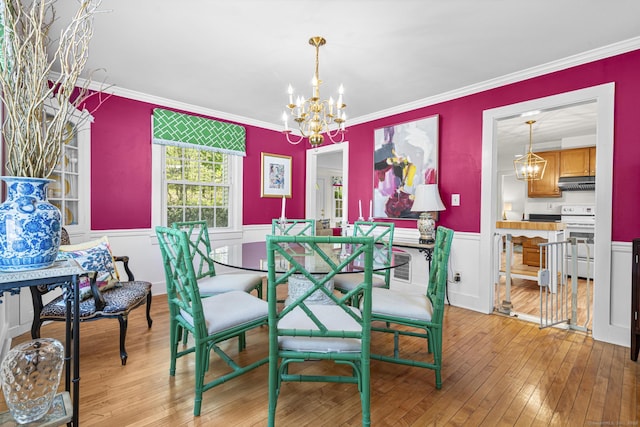 dining space with a notable chandelier, wainscoting, ornamental molding, and light wood finished floors