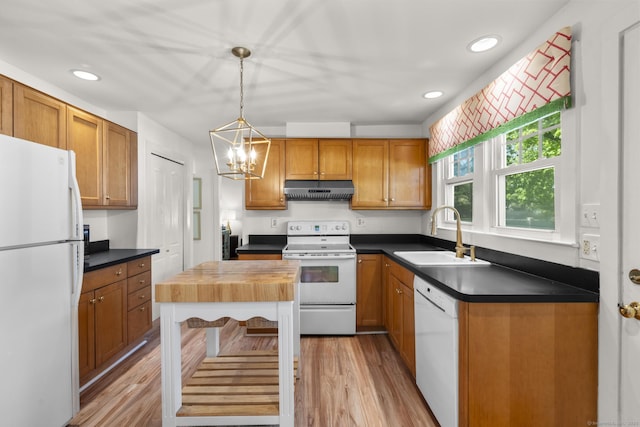 kitchen featuring dark countertops, an inviting chandelier, a sink, white appliances, and light wood-style flooring