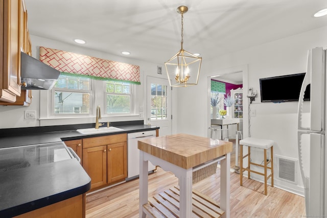 kitchen featuring visible vents, dark countertops, white appliances, a sink, and exhaust hood