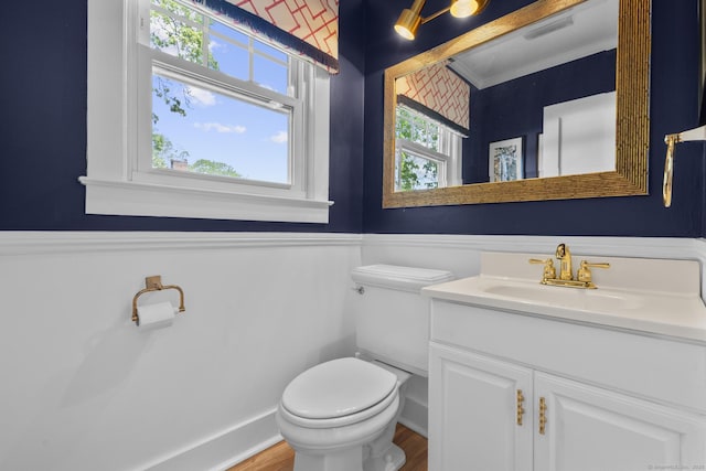 bathroom with vanity, a wainscoted wall, toilet, and wood finished floors