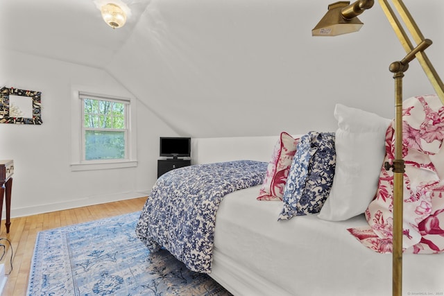 bedroom with baseboards, wood-type flooring, and vaulted ceiling