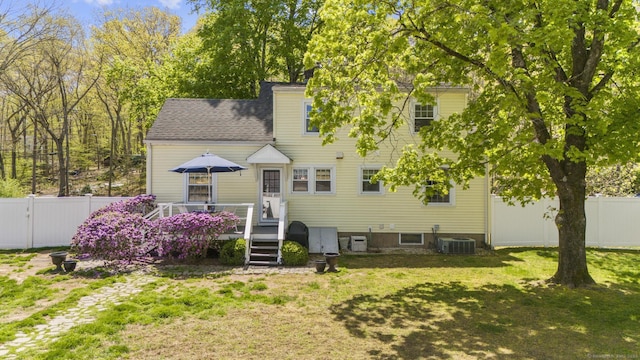 back of property featuring roof with shingles, a deck, a fenced backyard, cooling unit, and a yard