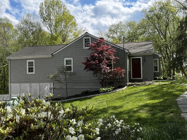 rear view of property featuring a yard and a shingled roof