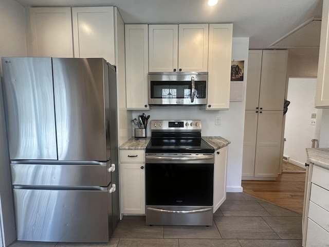 kitchen featuring appliances with stainless steel finishes, white cabinetry, light stone countertops, baseboards, and recessed lighting