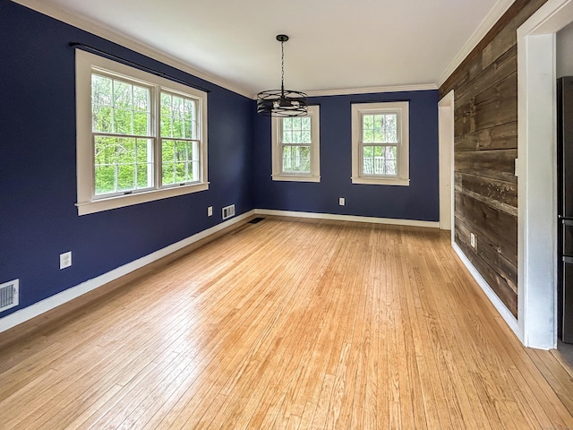 unfurnished room with ornamental molding, wood-type flooring, a chandelier, and baseboards