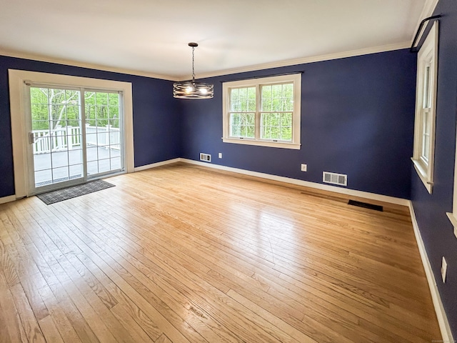 empty room with crown molding, light wood-style floors, baseboards, and a chandelier