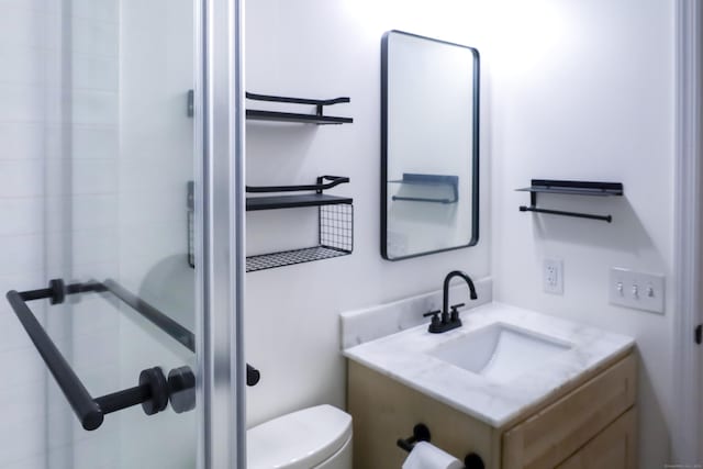 bathroom with vanity, a stall shower, and toilet