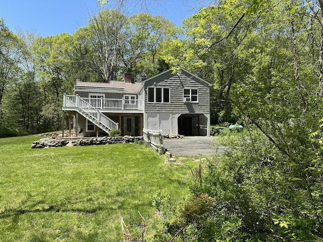 rear view of property featuring stairs, asphalt driveway, a carport, a deck, and a chimney