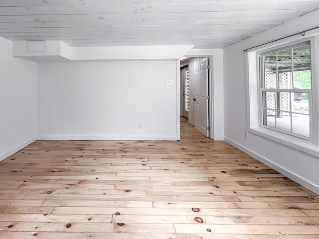 basement featuring light wood-type flooring, baseboards, and wooden ceiling