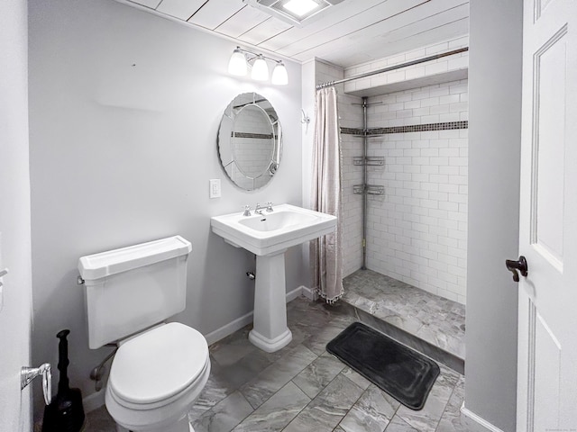 bathroom featuring toilet, a stall shower, marble finish flooring, and baseboards