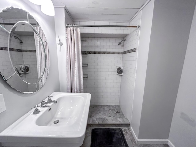 bathroom with tiled shower and a sink