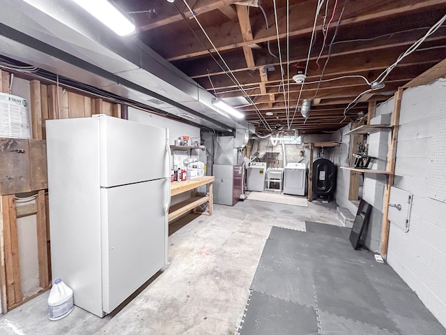 unfinished basement with freestanding refrigerator, heating unit, heating fuel, and independent washer and dryer
