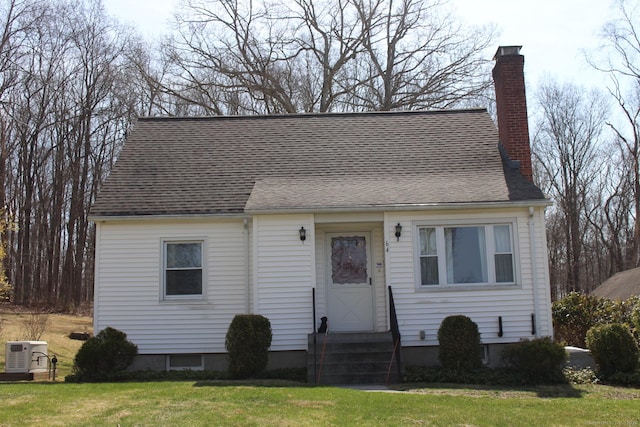 cape cod home with a chimney, a front yard, and a shingled roof
