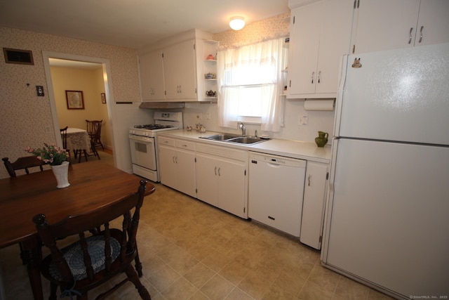 kitchen featuring white cabinets, a sink, light countertops, wallpapered walls, and white appliances