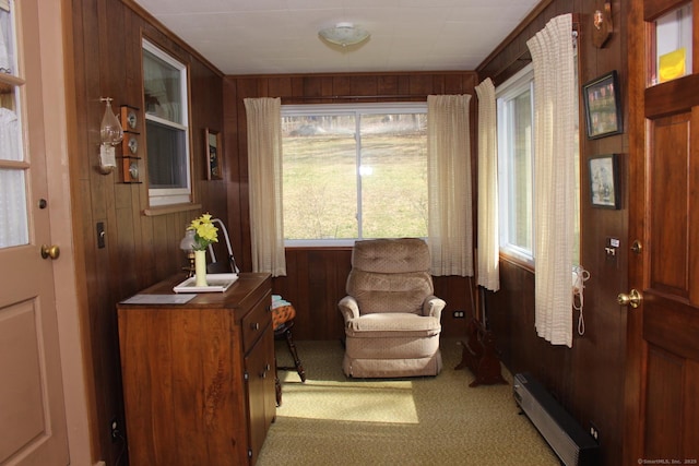 sitting room featuring wood walls, light carpet, and a baseboard radiator