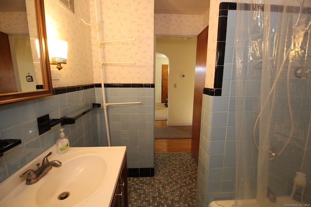 bathroom with wallpapered walls, a shower with curtain, tile walls, vanity, and visible vents