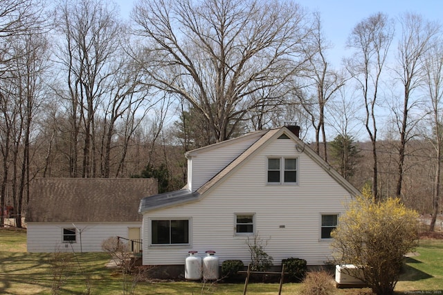 view of property exterior featuring a chimney and a yard