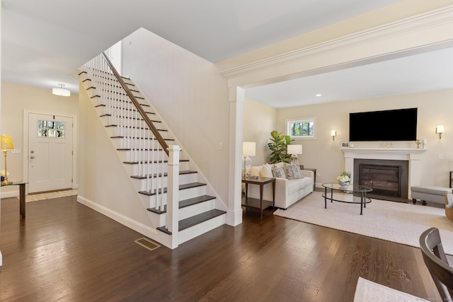 interior space featuring visible vents, stairs, a glass covered fireplace, and wood finished floors