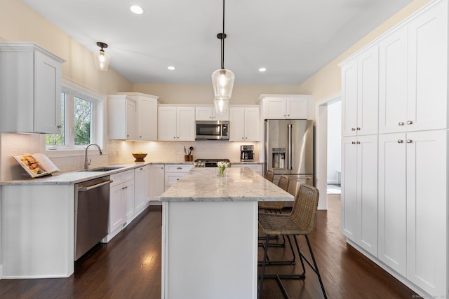 kitchen featuring backsplash, a center island, a sink, white cabinets, and stainless steel appliances