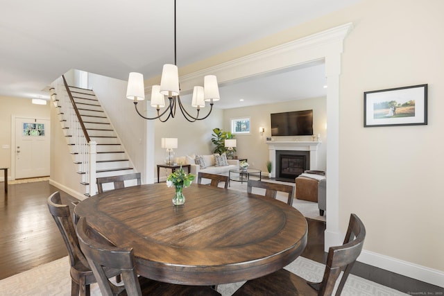 dining room with stairs, baseboards, a notable chandelier, and wood finished floors