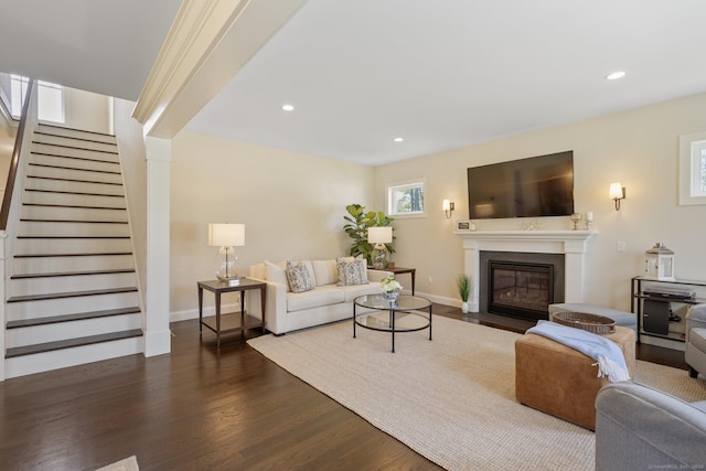 living area featuring recessed lighting, a fireplace with flush hearth, dark wood finished floors, and stairs