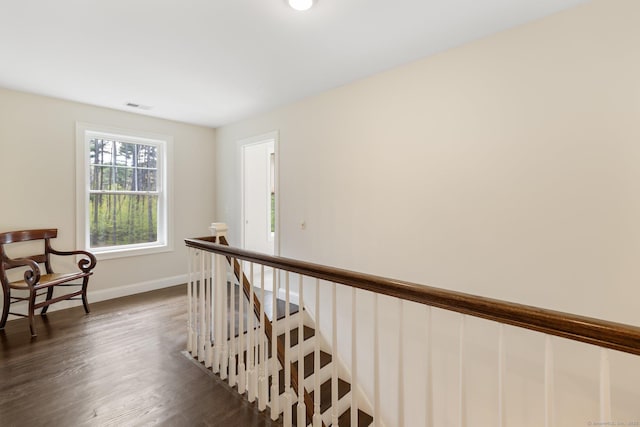 corridor featuring visible vents, baseboards, dark wood-type flooring, and an upstairs landing