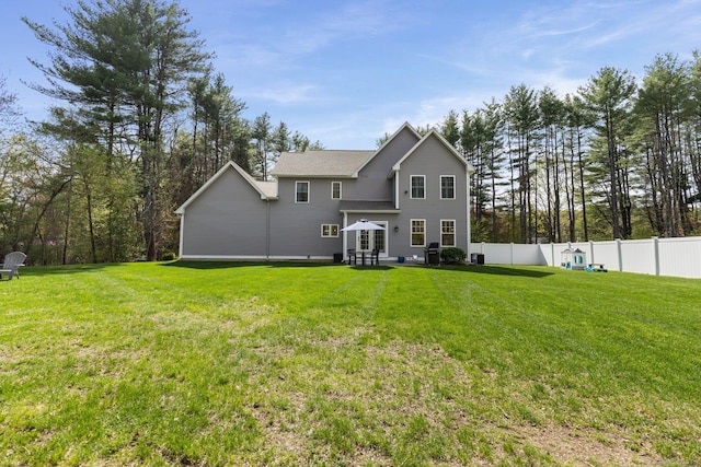 rear view of house featuring fence, a yard, and entry steps