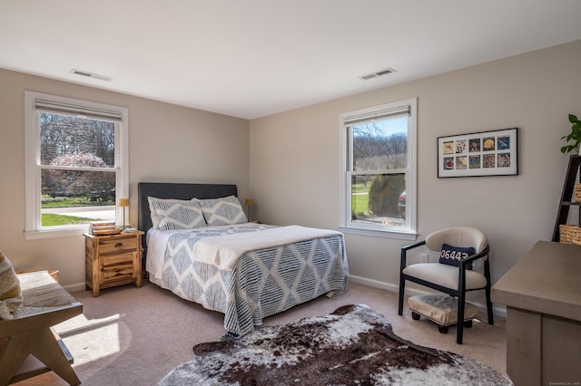bedroom with visible vents, multiple windows, and light colored carpet