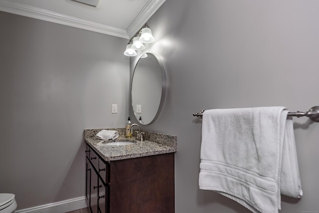 half bathroom with baseboards, toilet, crown molding, and vanity