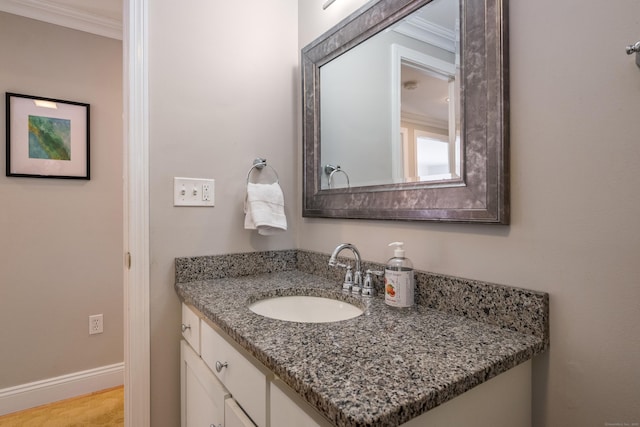 bathroom with baseboards, crown molding, and vanity
