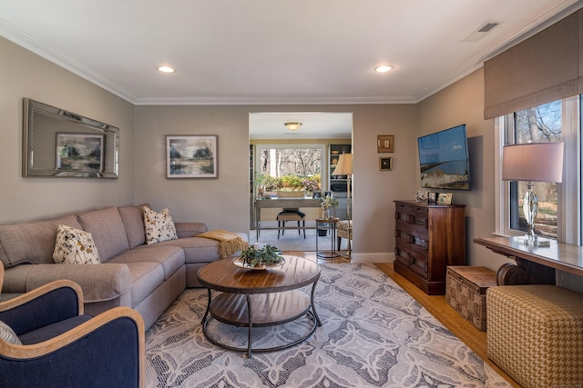 living room featuring a healthy amount of sunlight, recessed lighting, ornamental molding, and light wood-style floors