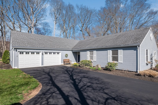 ranch-style house with a garage, driveway, and roof with shingles