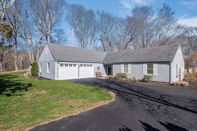ranch-style home featuring aphalt driveway, a shingled roof, a front yard, and an attached garage