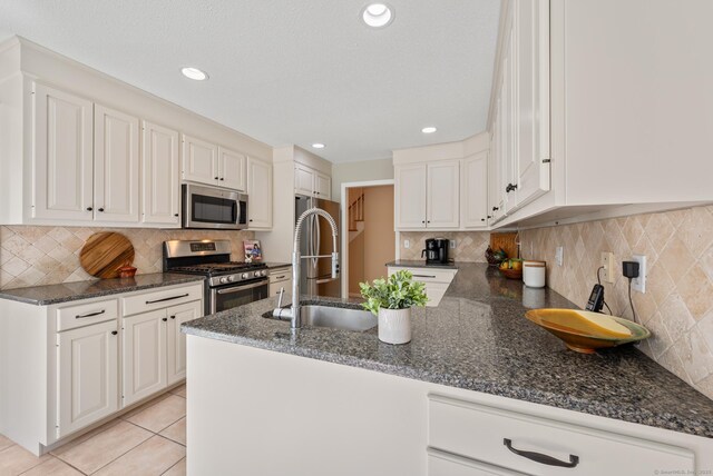 kitchen featuring appliances with stainless steel finishes, a sink, a peninsula, decorative backsplash, and recessed lighting