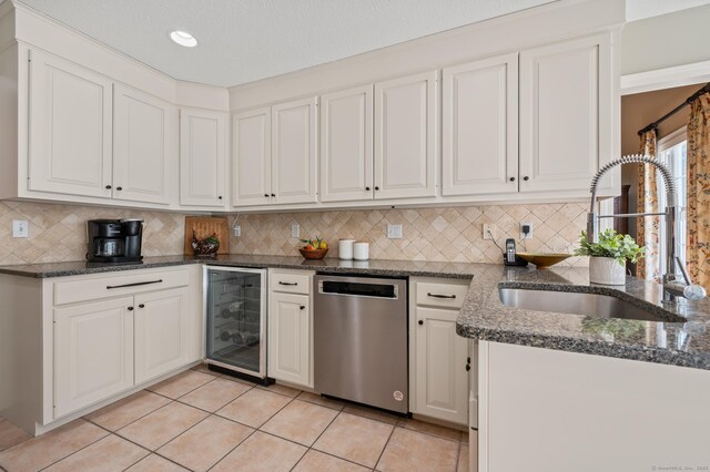 kitchen featuring dishwasher, wine cooler, a sink, white cabinetry, and tasteful backsplash