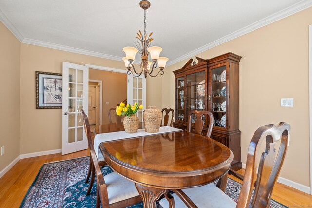 dining room featuring french doors, a chandelier, crown molding, light wood-type flooring, and baseboards