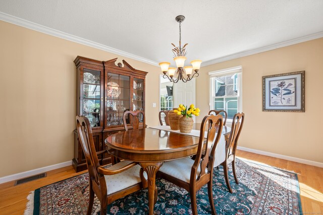 dining room featuring a chandelier, ornamental molding, wood finished floors, and baseboards