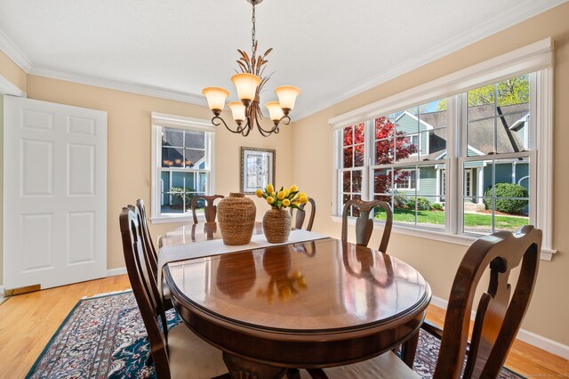 dining space featuring a chandelier, crown molding, healthy amount of natural light, baseboards, and light wood-style floors