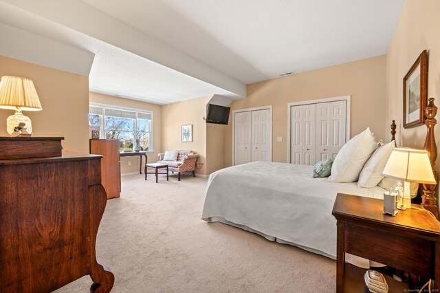 carpeted bedroom featuring multiple closets and baseboards