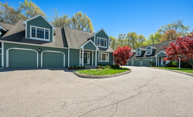 view of front of house with driveway, a garage, and roof with shingles