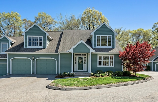 view of front facade with an attached garage, asphalt driveway, roof with shingles, and a front yard