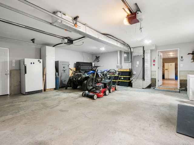 garage with a garage door opener, freestanding refrigerator, white fridge with ice dispenser, and electric panel