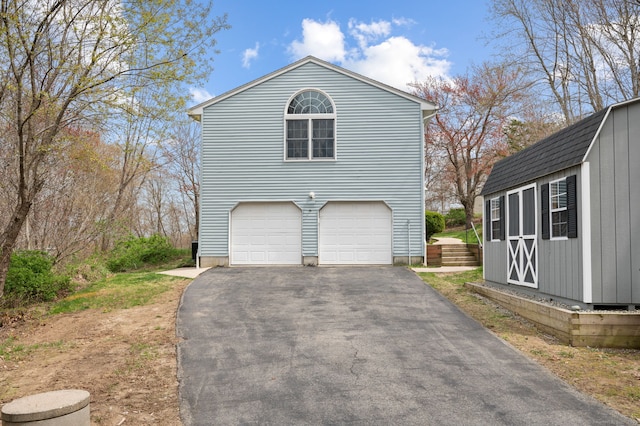 view of side of home featuring an outbuilding, an attached garage, and driveway