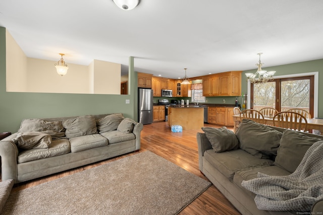 living area with light wood-style floors, an inviting chandelier, and a wealth of natural light
